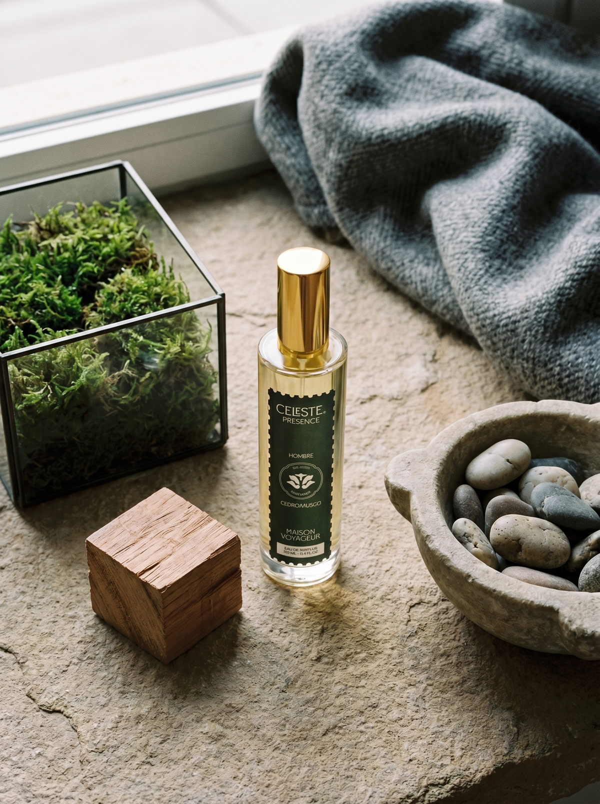 Presence eau de parfum 100ml lifestyle on Madrid raw stone surface with cedar wood block and moss terrarium — Maison Voyageur Mediterranean artisanal parfumerie